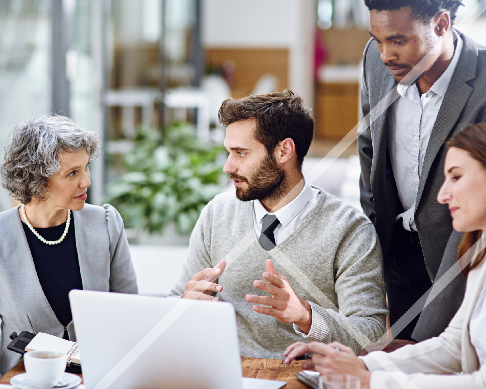 Team of people in a professional setting having a discussion around a laptop