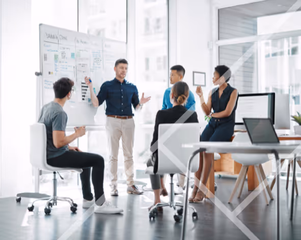 Team of professional people sitting and standing around a whiteboard in a large office with big windows