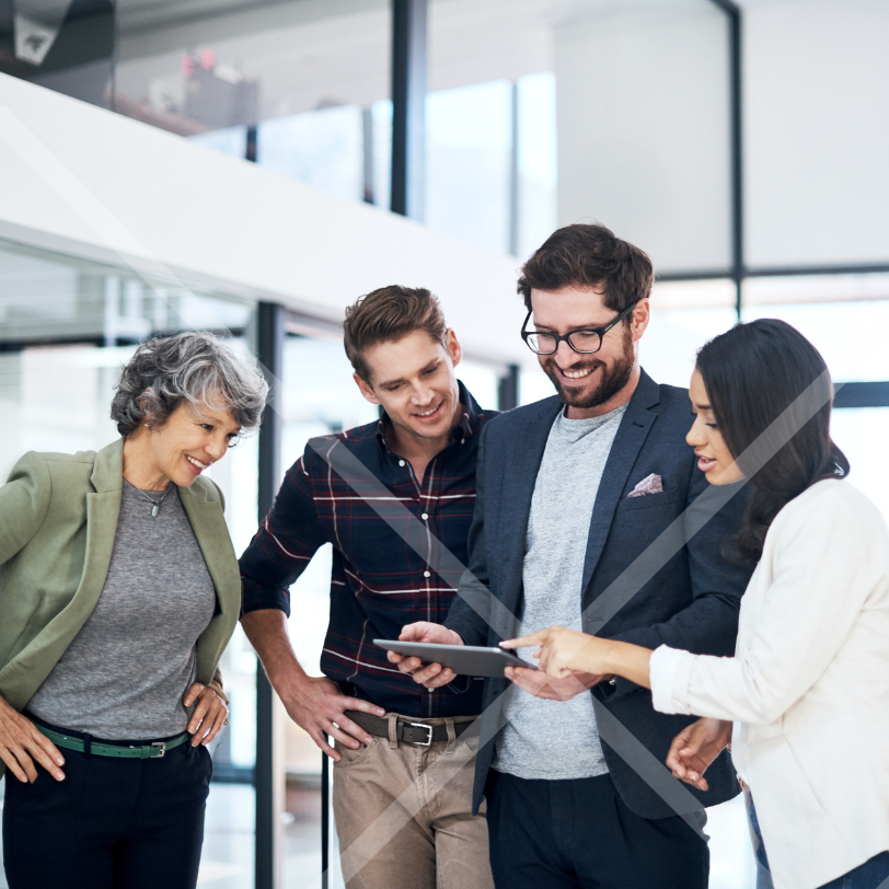 A group of men and women in a coporate setting looking at a digital tablet