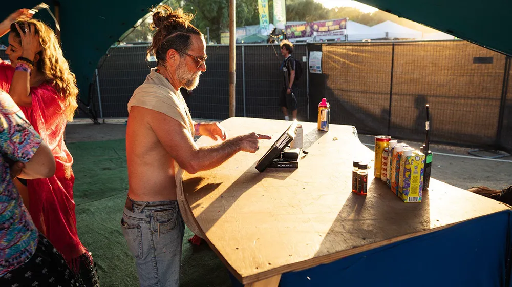 Festival attendee using a Billfold POS terminal at a vendor booth during sunset