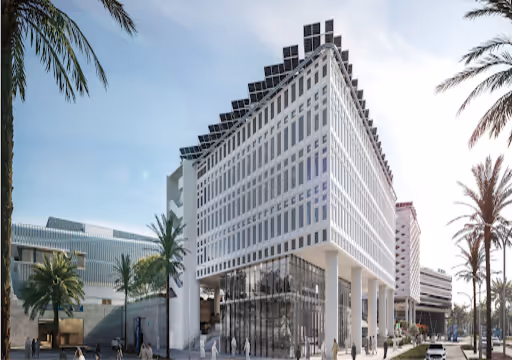 Modern building with white facade and rooftop solar panels surrounded by palm trees under a blue sky.