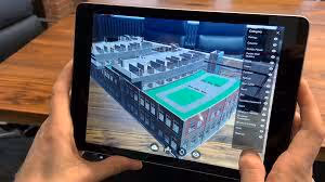Person holding tablet showing 3D building model with rooftop tennis courts in augmented reality.
