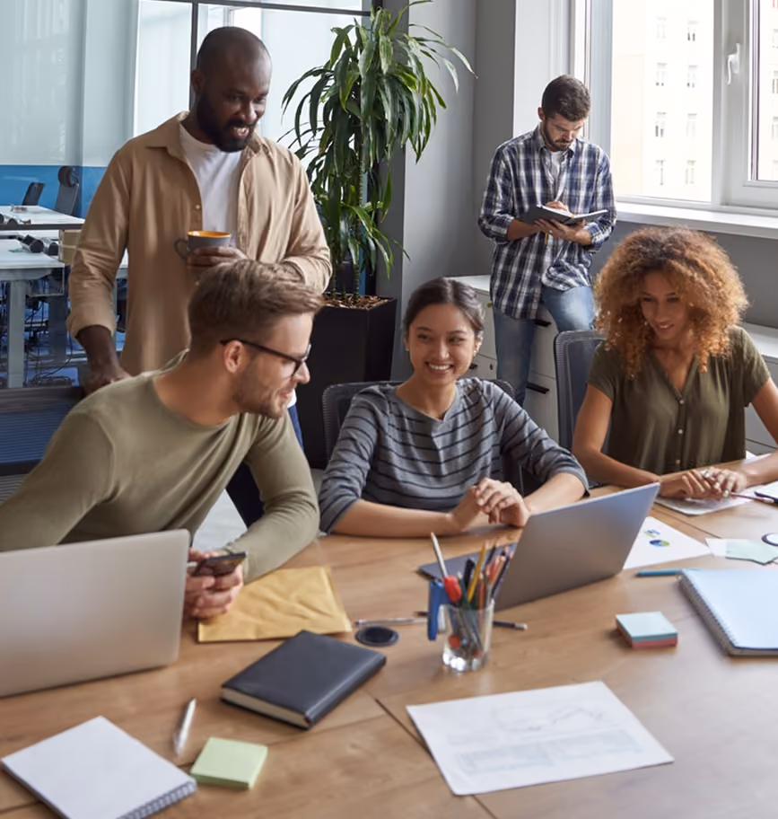 Coworkers gathered around a laptop collaborating in an office