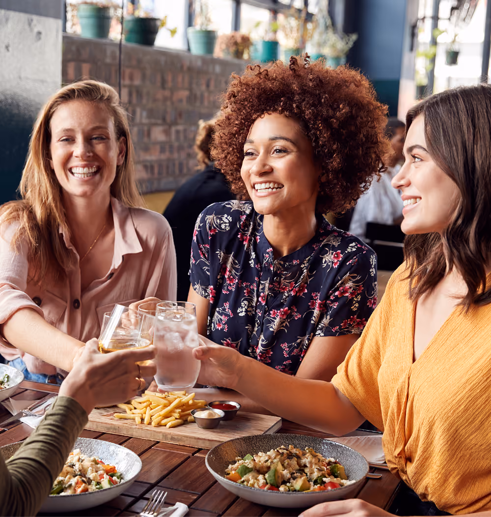 Three women toasting drinks at a restaurant table