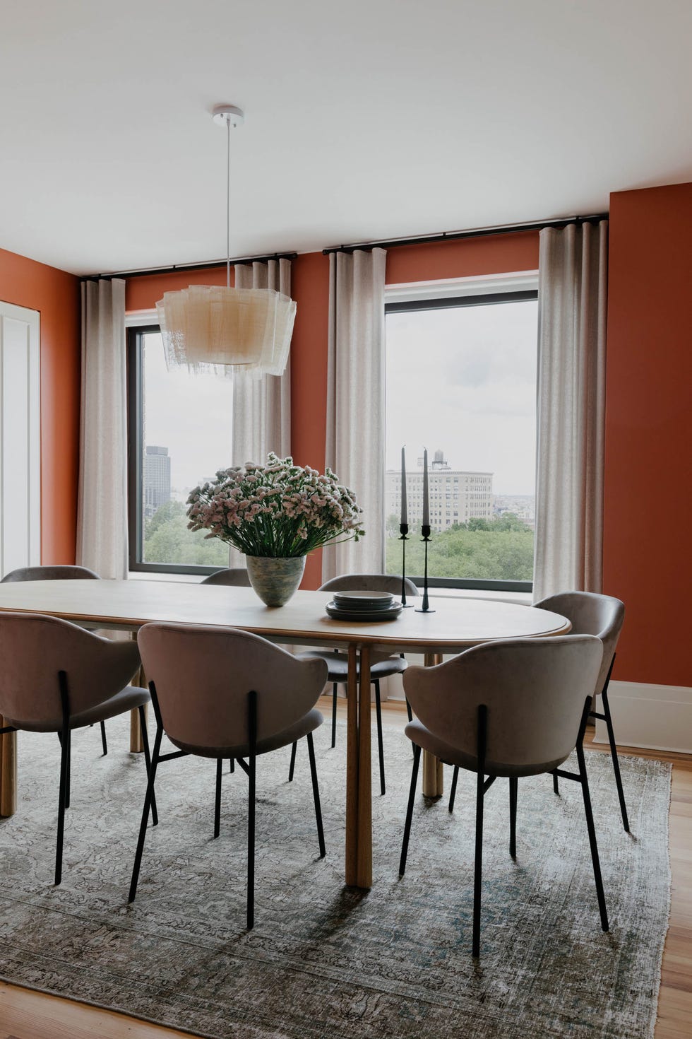 a modern dining area with a wooden table upholstered chairs and red walls