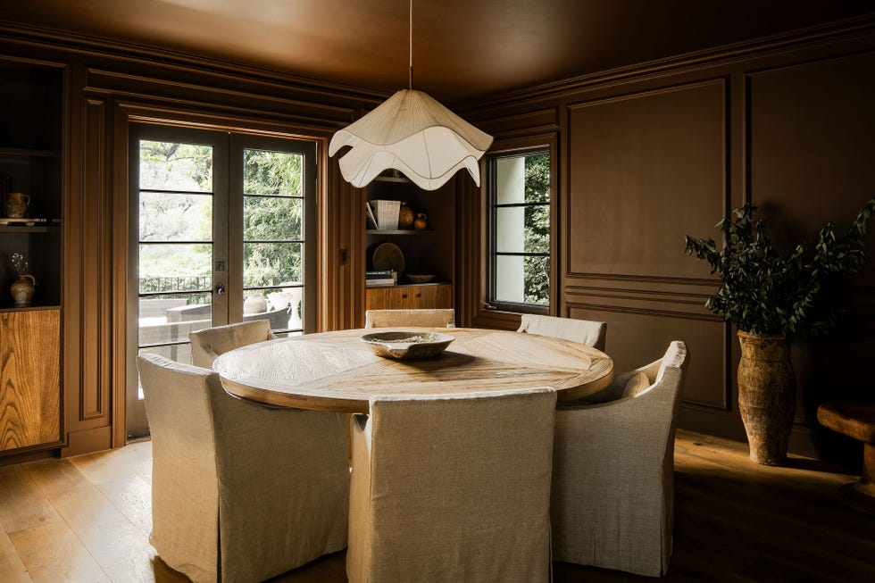 dining area featuring a round wooden table and upholstered chairs and dark brown walls