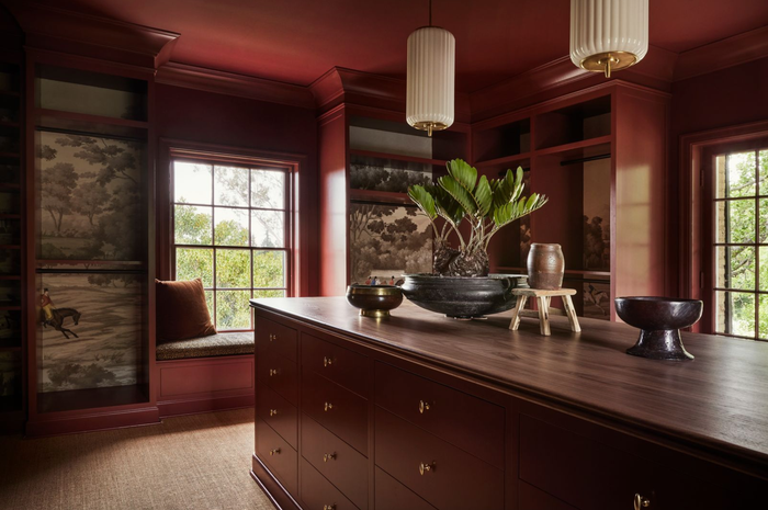 Elegant room with red cabinetry, window seat, and decorative items on a wooden island.