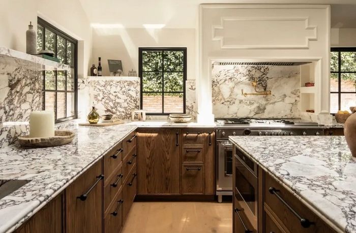 Modern kitchen with marble countertops, wooden cabinets, and large windows.