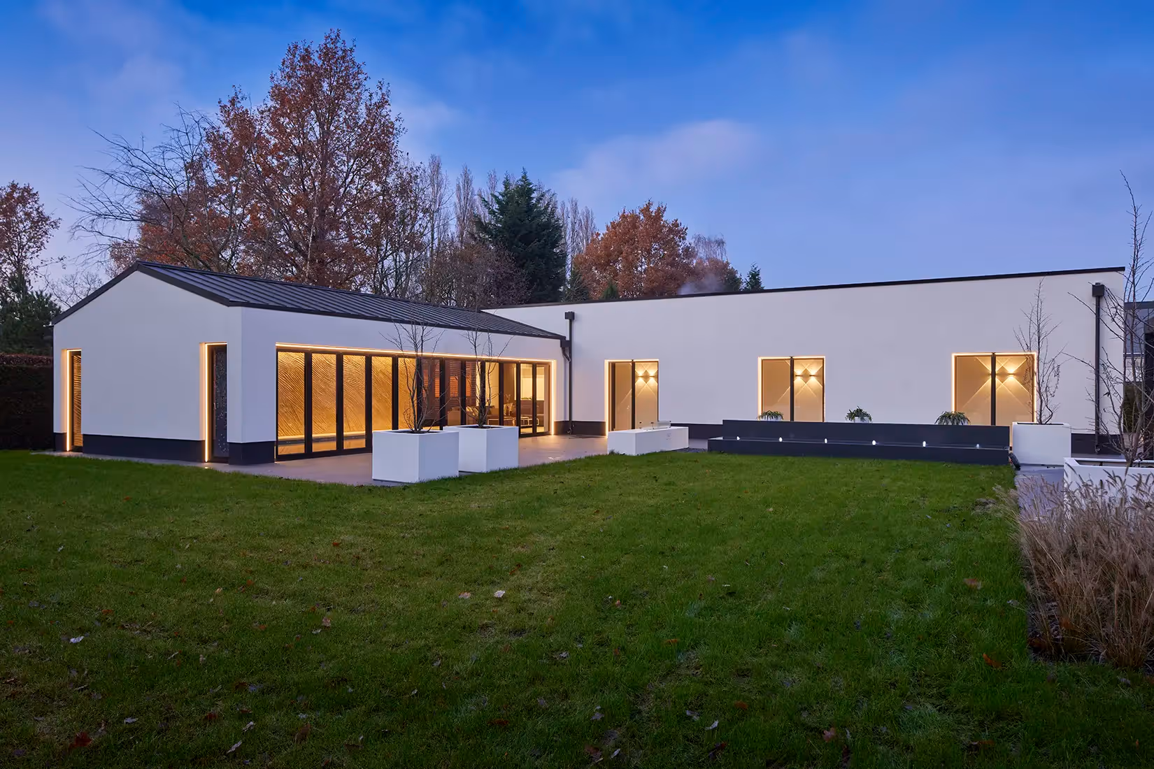 Verlichting van een gebouw met een binnenzwembad in schemersetting.