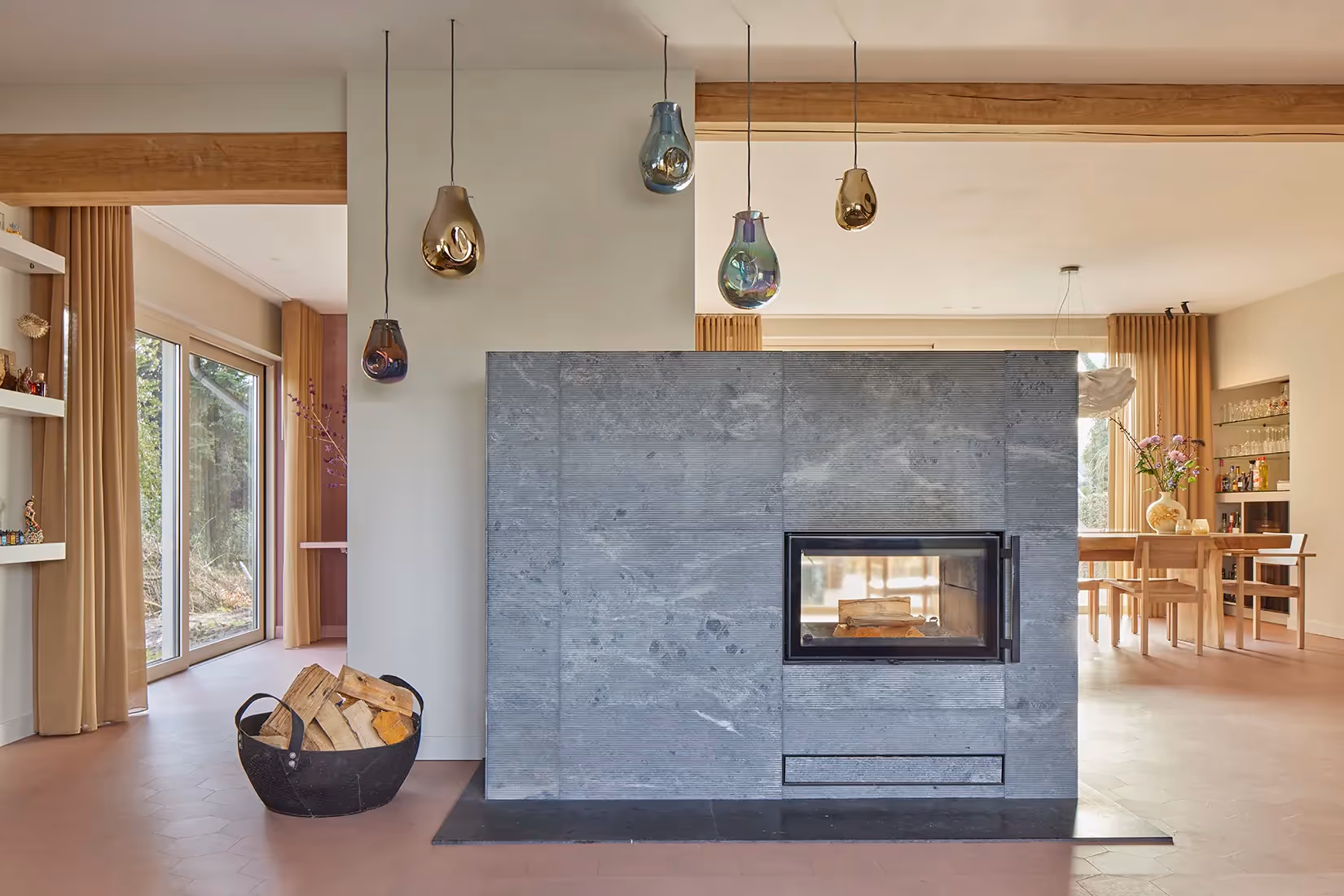 Woonkamer met elegante mondgeblazen glazen hangarmaturen boven houthaard.