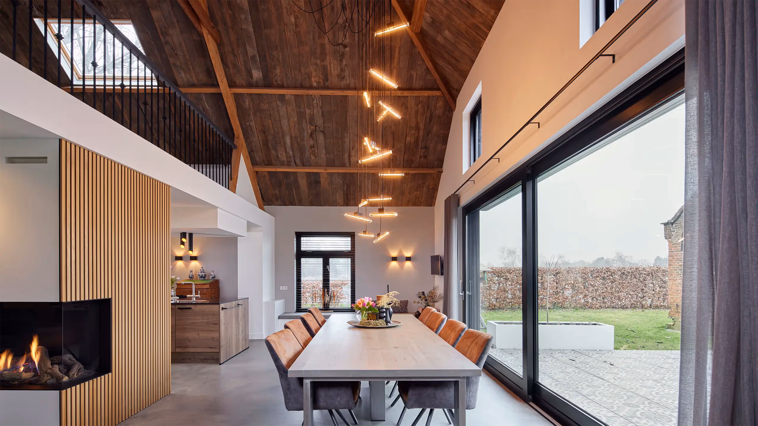 Geclusterde hanglamp als verlichting in vide met houten plafond.