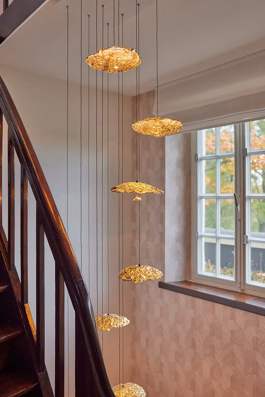 Doorkijk naar geclusterde hangarmaturen als hal- en trapverlcihting.