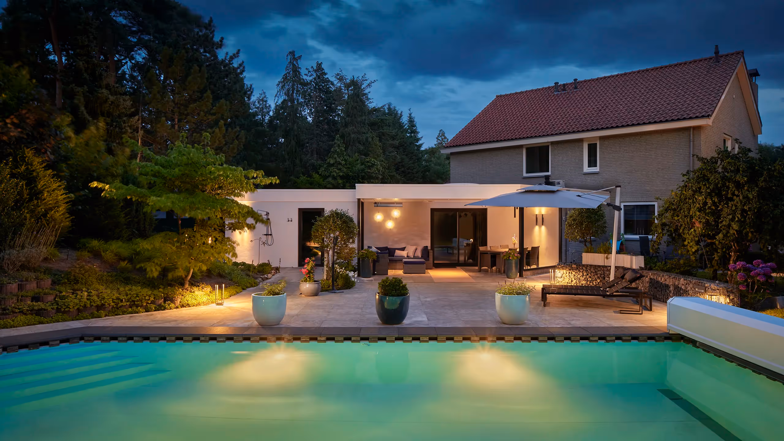 Sfeervolle tuinverlichting met wandarmaturen, plafondspot en vloerlampen.