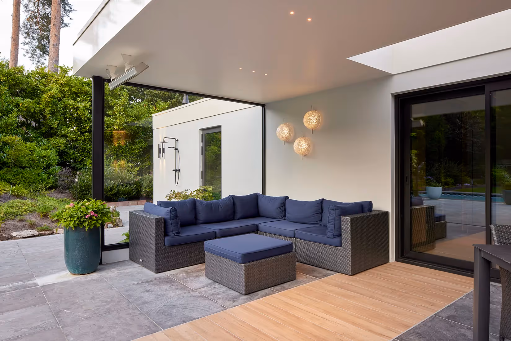 Buitenzithoek onder overkapping voorzien van plafondspots als basisverlichting en sfeerverhogende artistieke wandarmaturen.