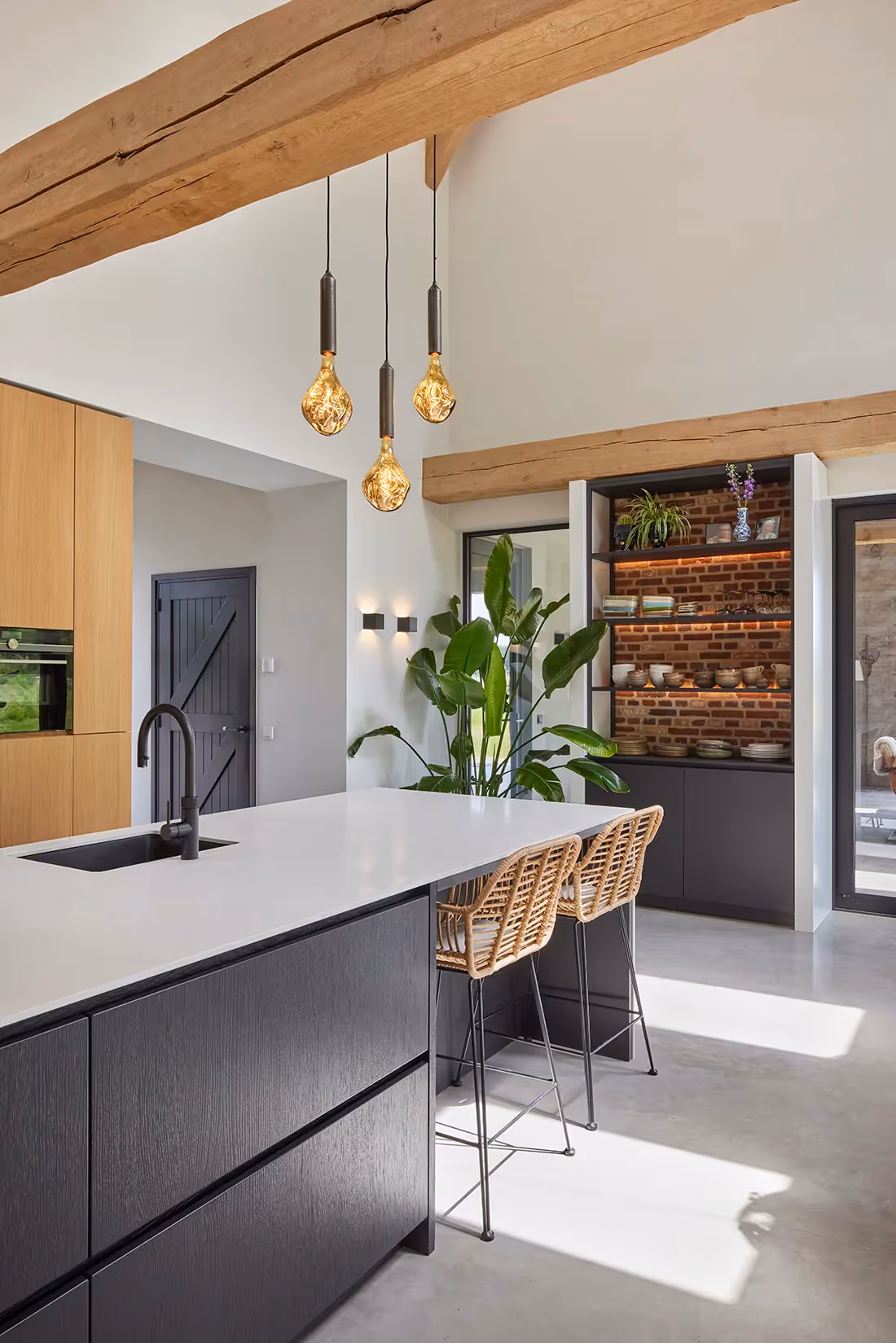 Keuken met wand- en nisverlichting en hangarmaturen boven het eiland..