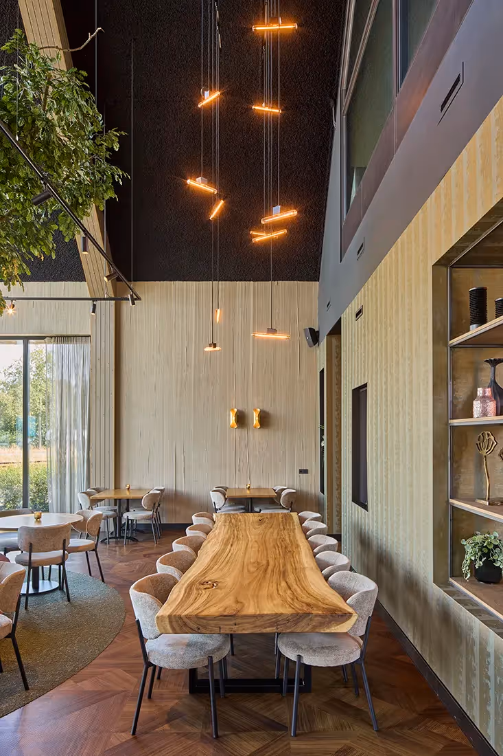 Gegroepeerde hangarmaturen boven een lange dinertafel.