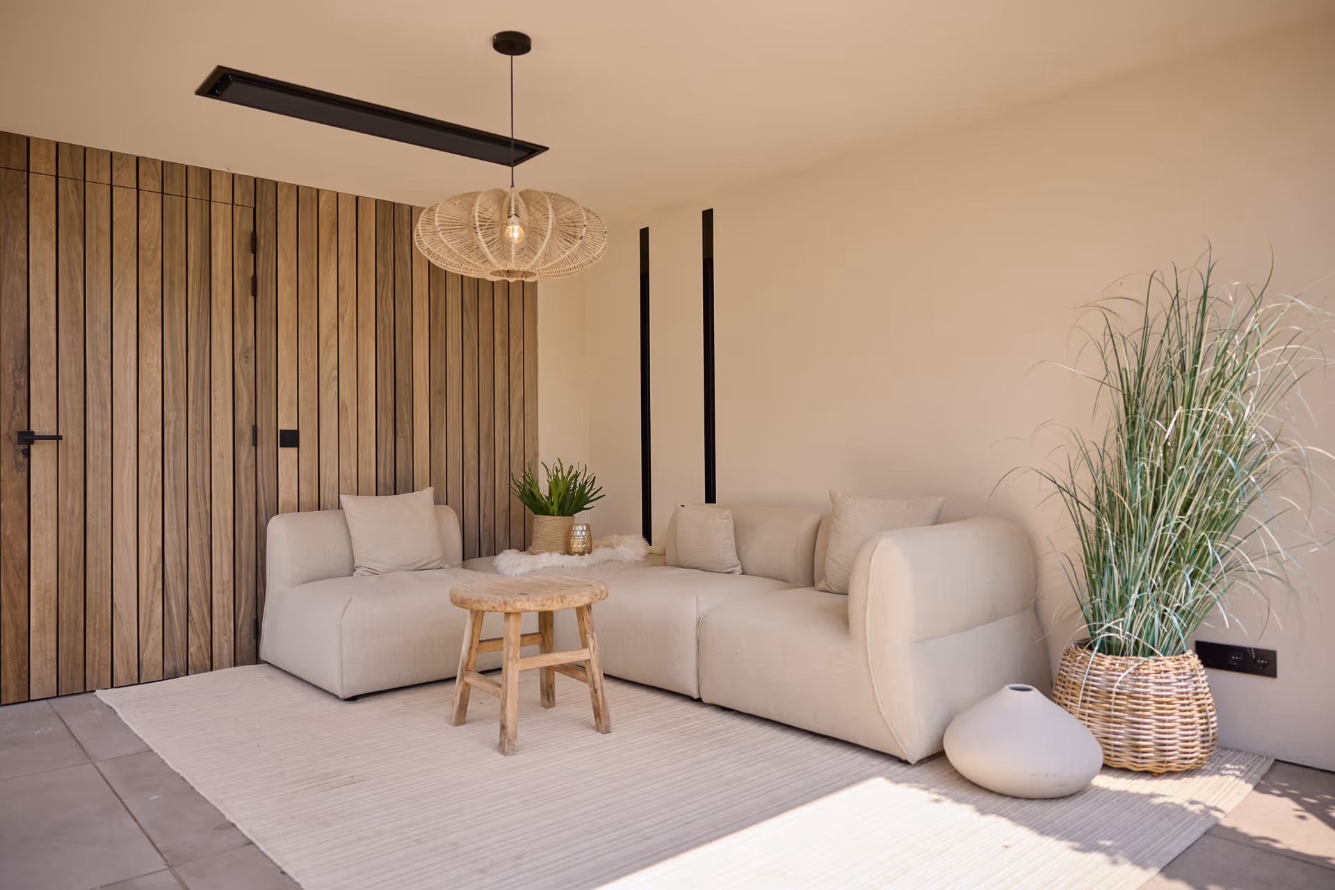 Overkapte lounge in beach-stijl, verlicht door zomerse hanglamp en strakke verdiepte wandverlichting.