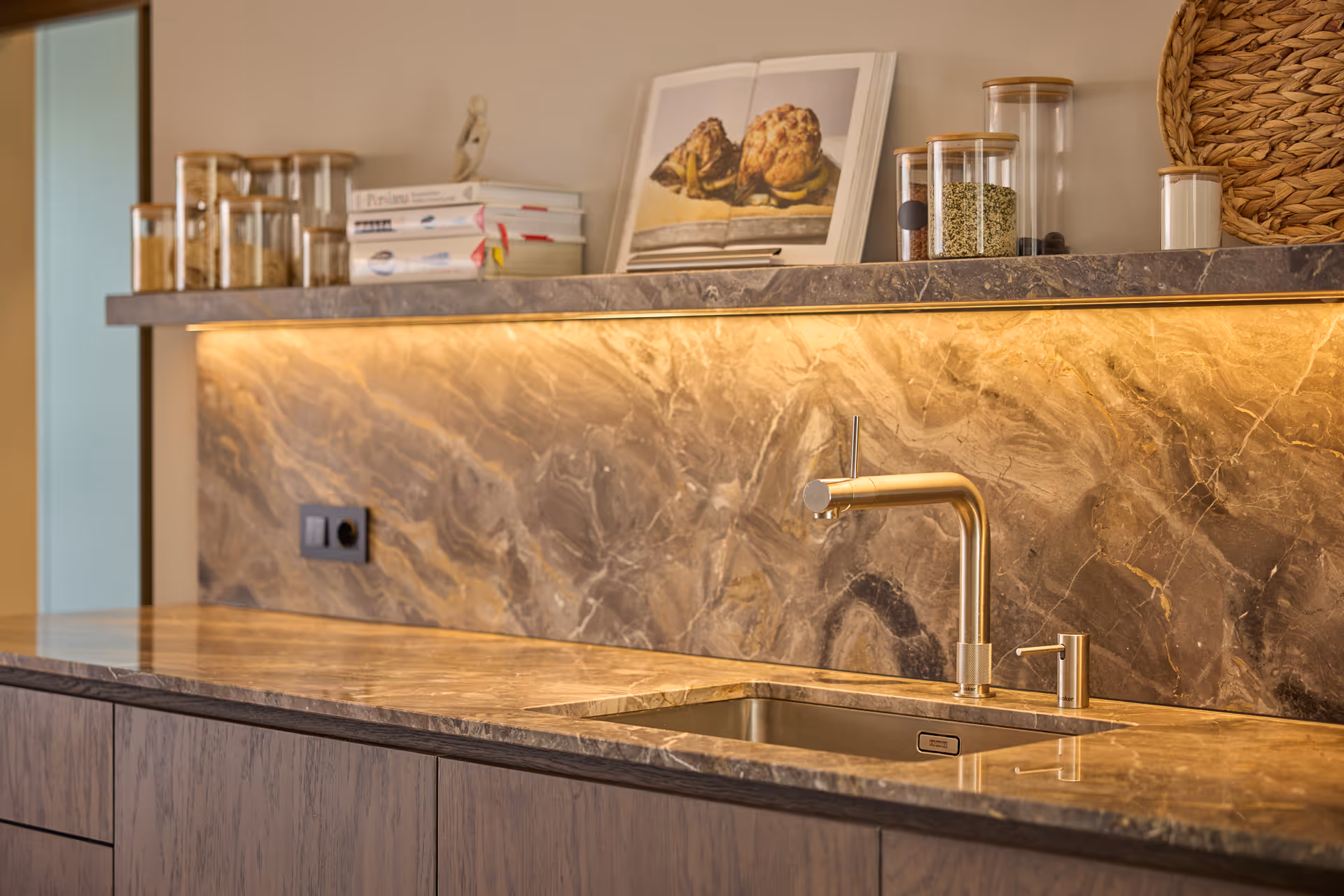 Marmeren keukenblad en achterwand met geïntegreerde ledlijnverlichting die het werkvlak warm en egaal uitlicht.