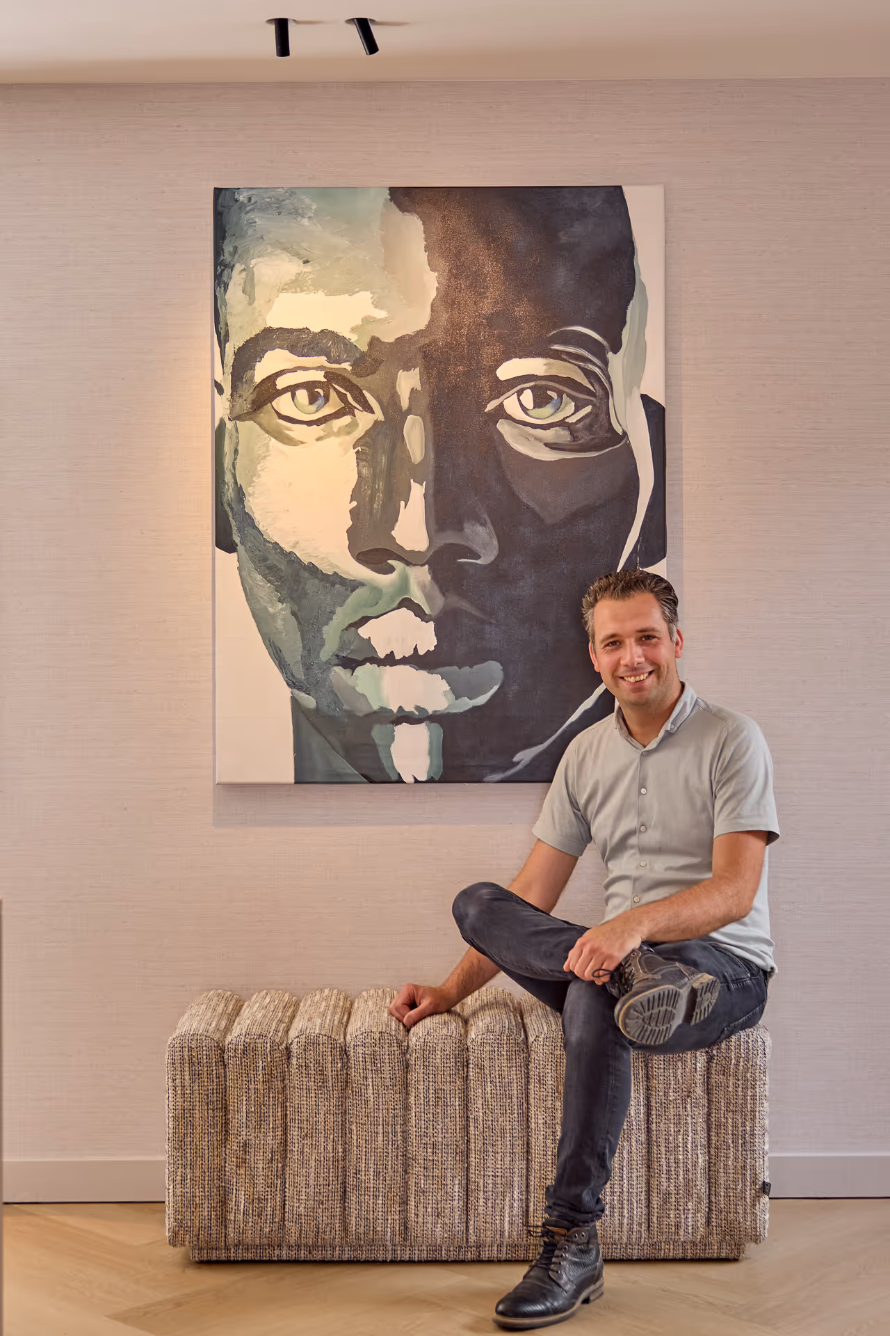 Kunstwerk en richtspots die het portret en de wand warm accentueren.