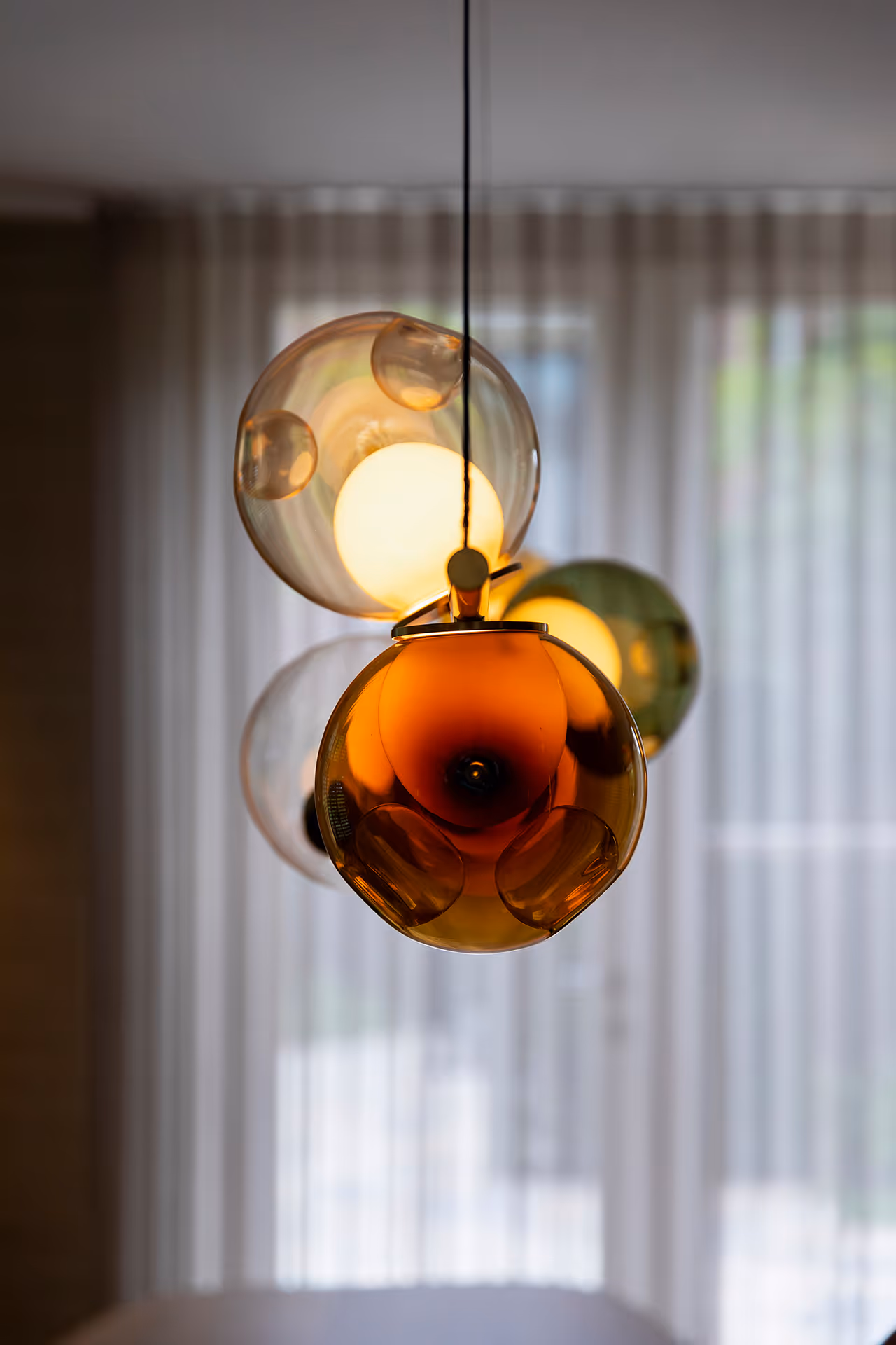 Close up van designhanglamp met glazen bollen die warm licht verspreiden.