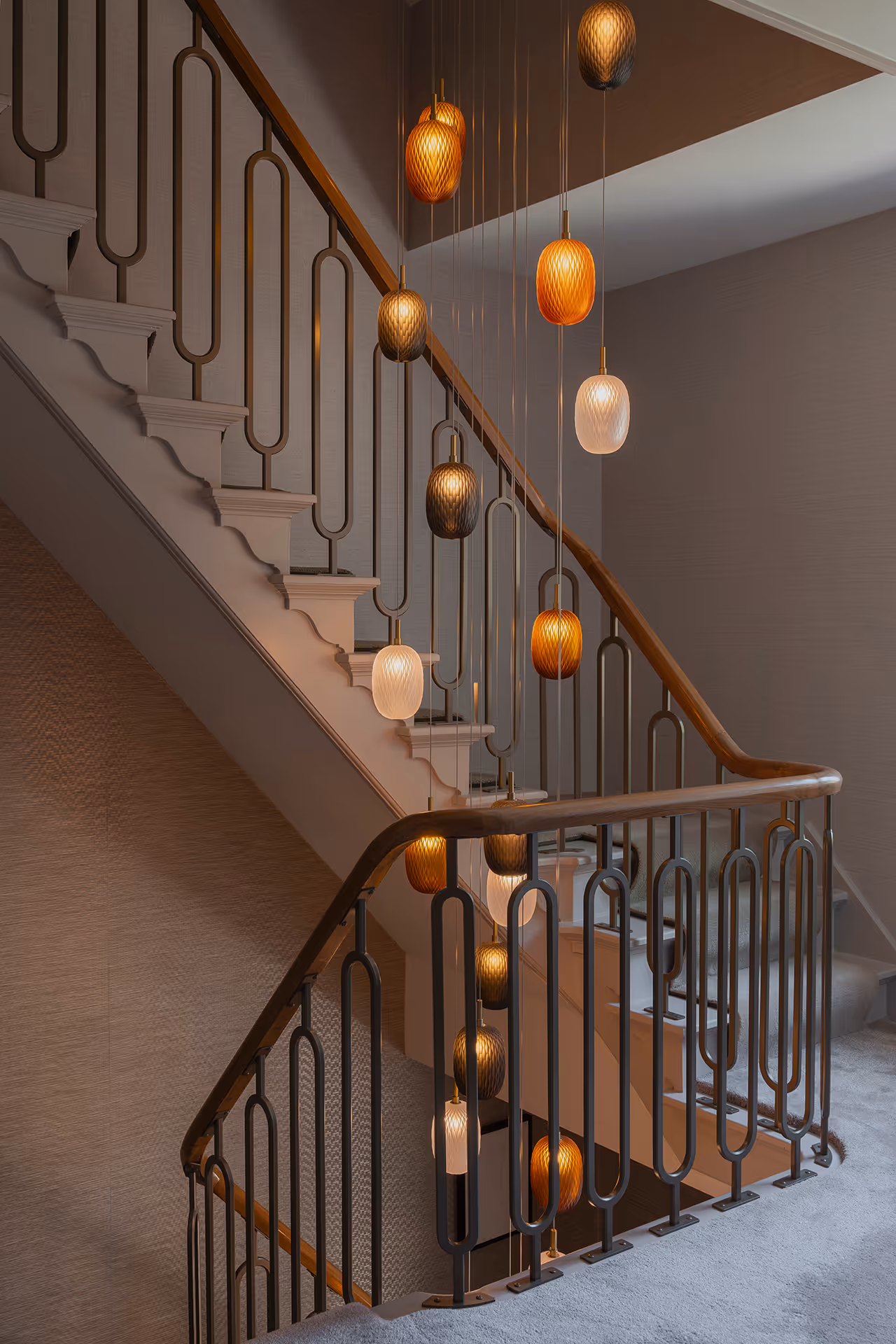 Perspectief zijaanzicht van trappenhuis met glasarmaturen op verschillende hoogtes met sfeervol lichtbeeld.