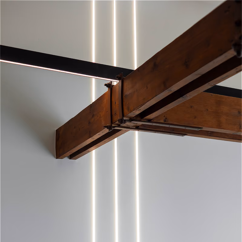 Drie verticale lichtlijnen onder een verbindingspunt van twee massieve houten balken.
