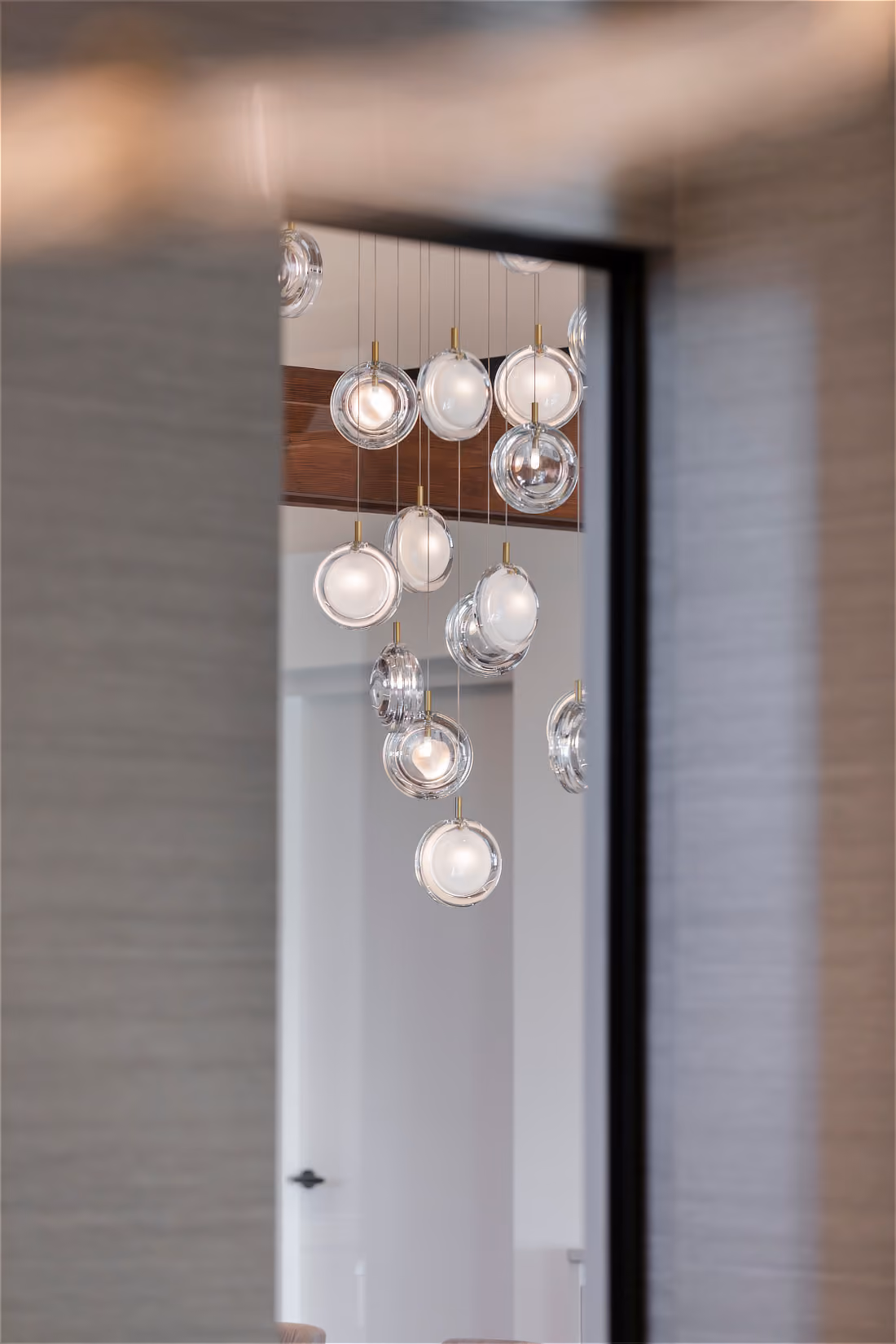 Doorkijk via een glazen deuropening naar de sprankelende cluster gebolde glazen lenzen met warme lichtpunten.