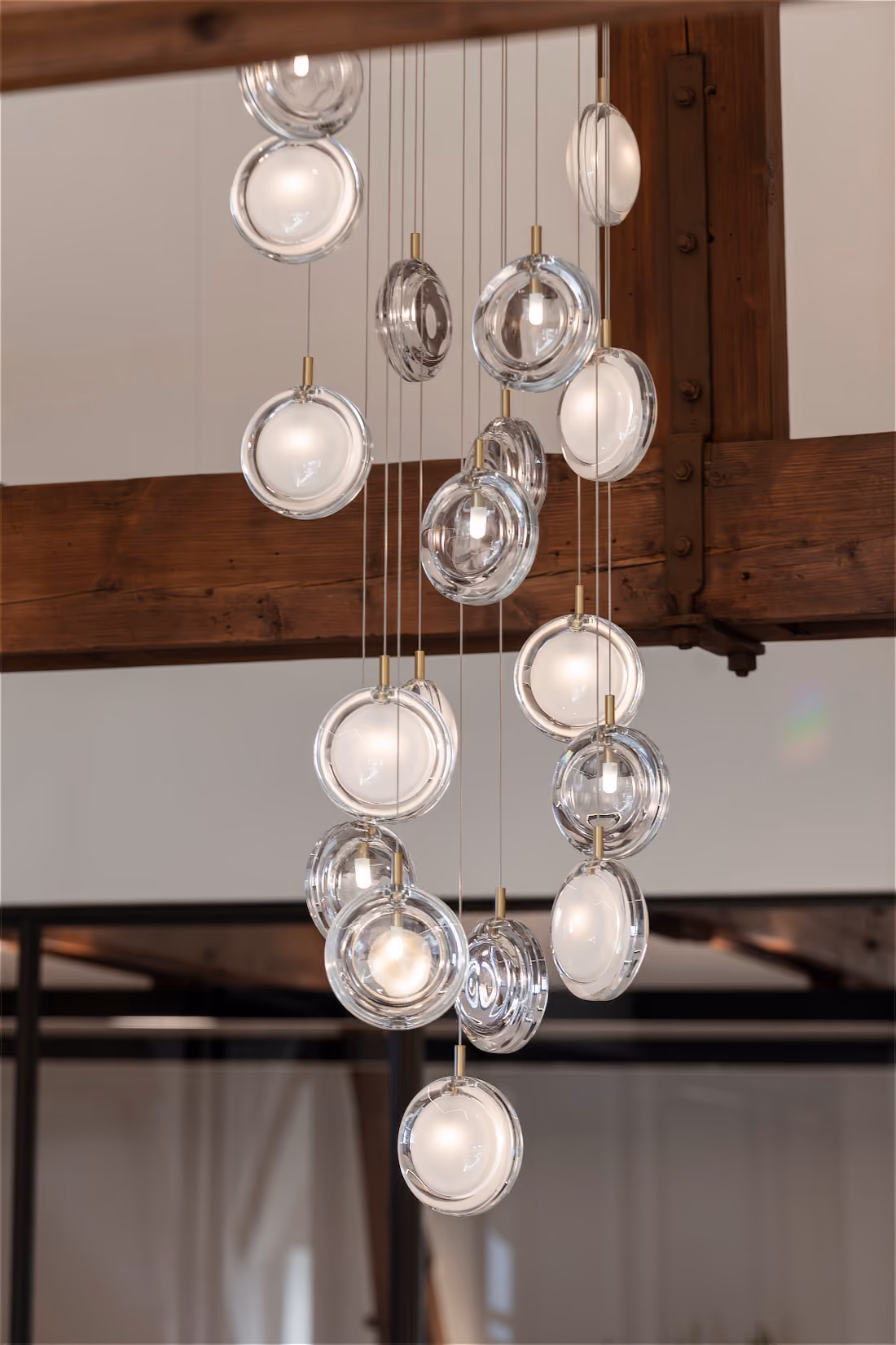 Volledige cluster gebolde glazen lenzen, hangend onder een robuuste houten dakconstructie.