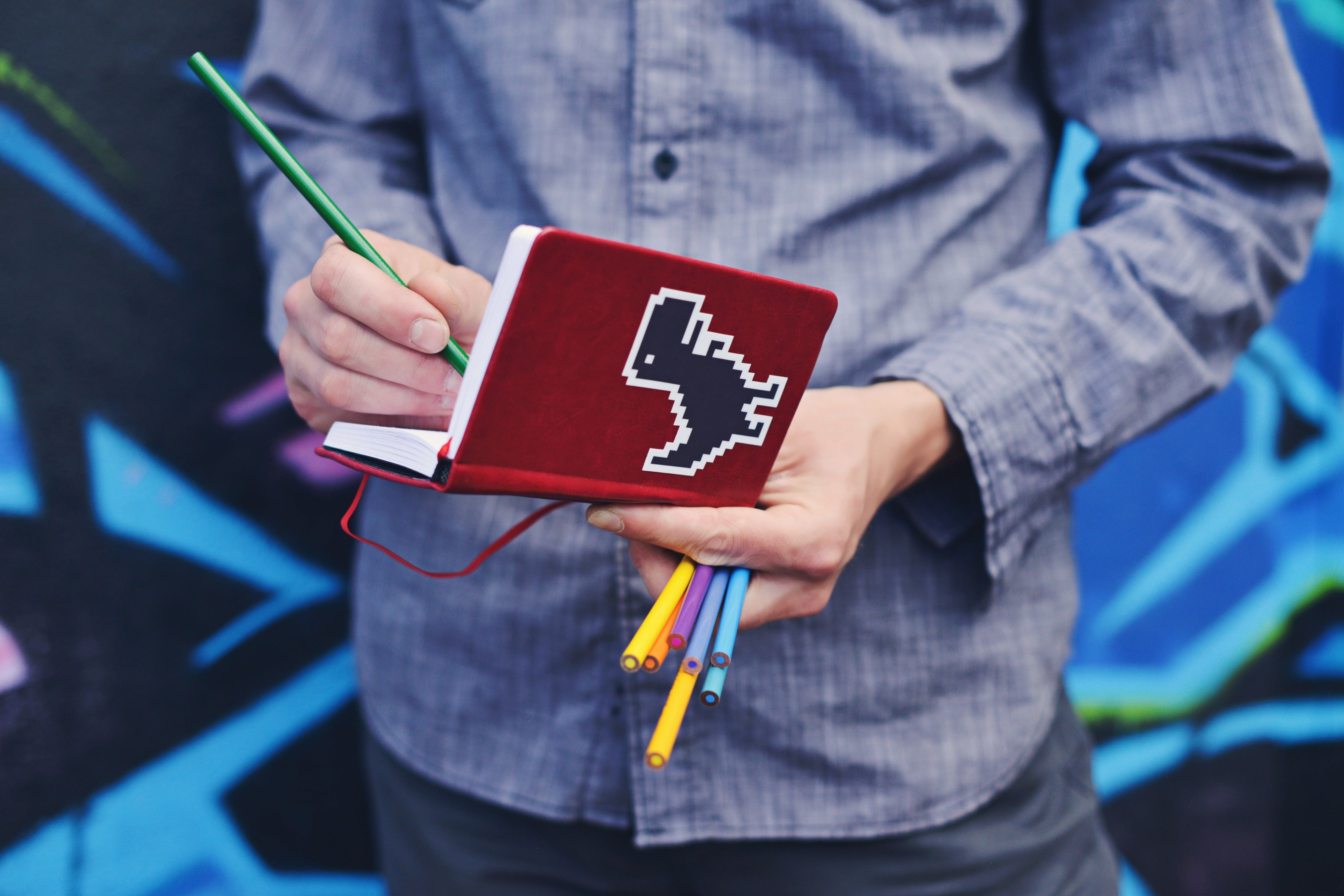 A person writing on a notebook with color pencils, photographed by Sticker Mule