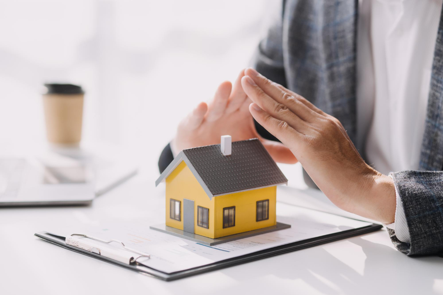 person holding hands over a miniature house