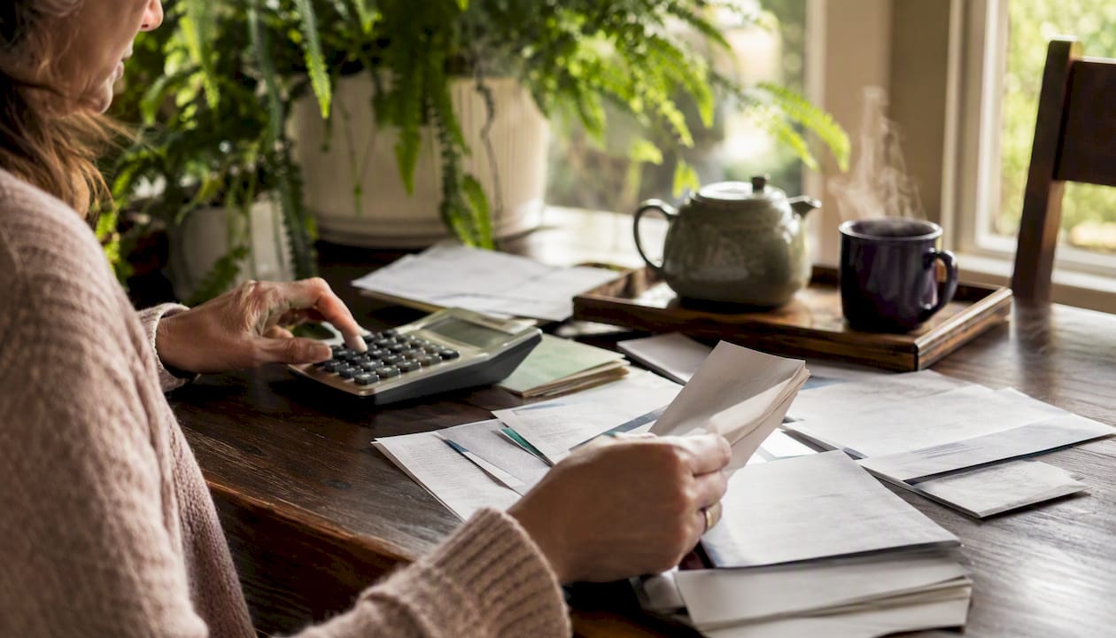 Hands using calculator with bills on kitchen table