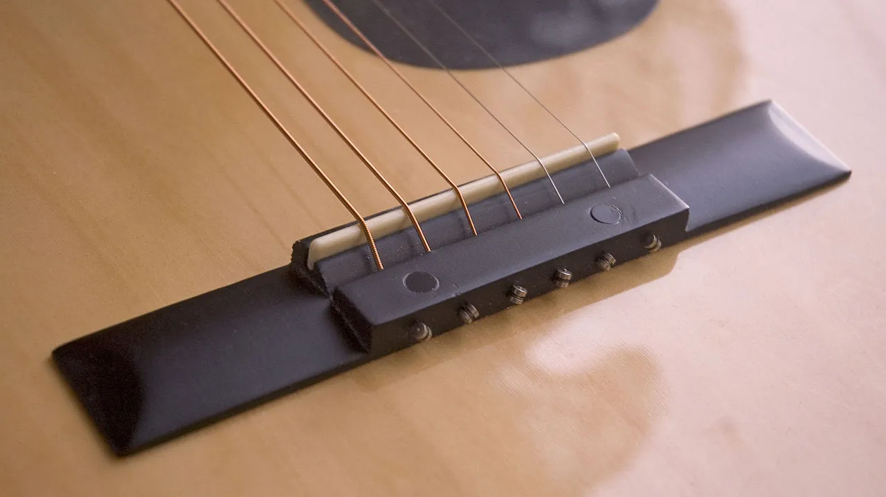 A guitar bridge is used to transfer the vibrations of the strings to the frame