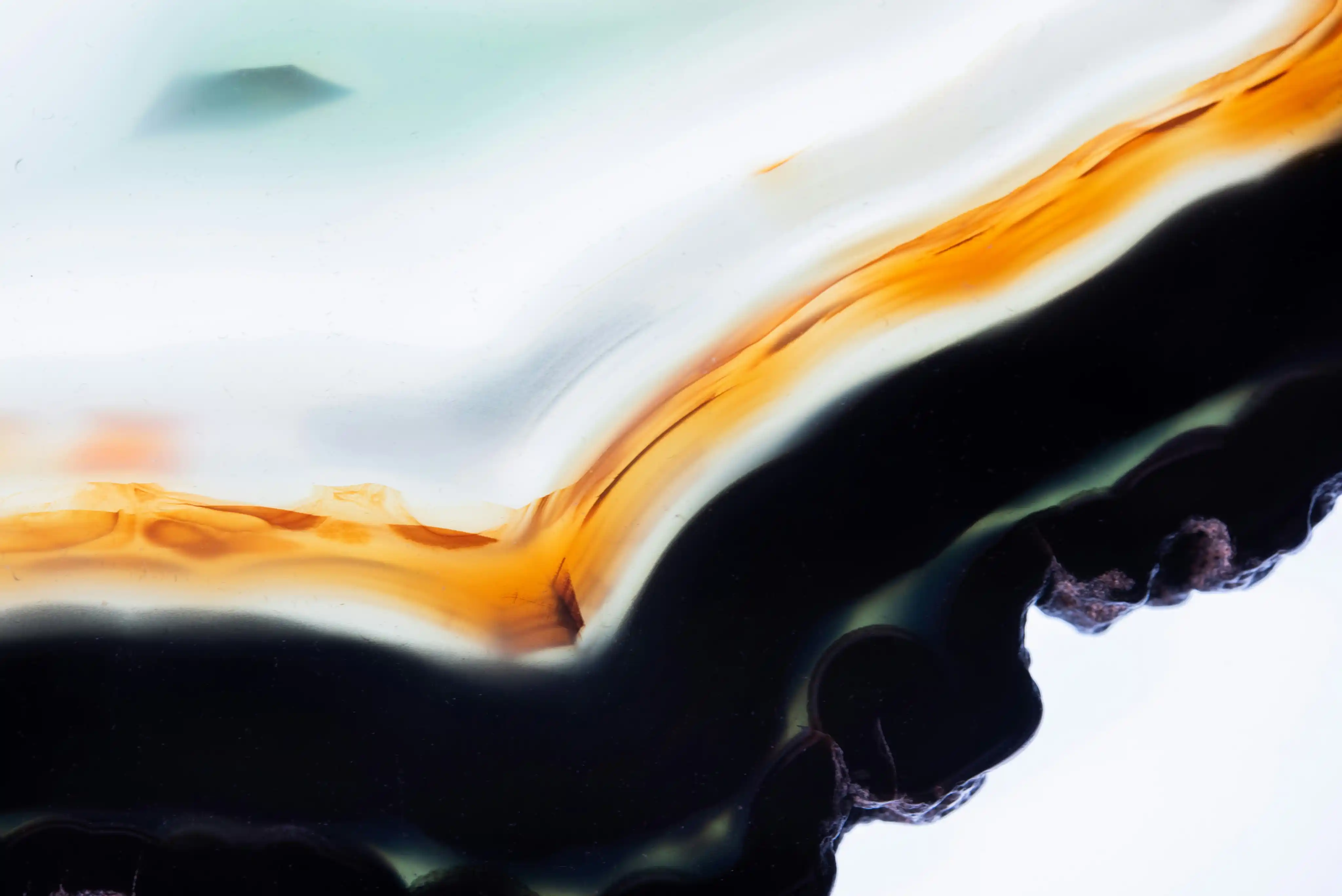 Close-up of a polished agate stone showing layers in orange, black, and white colors.