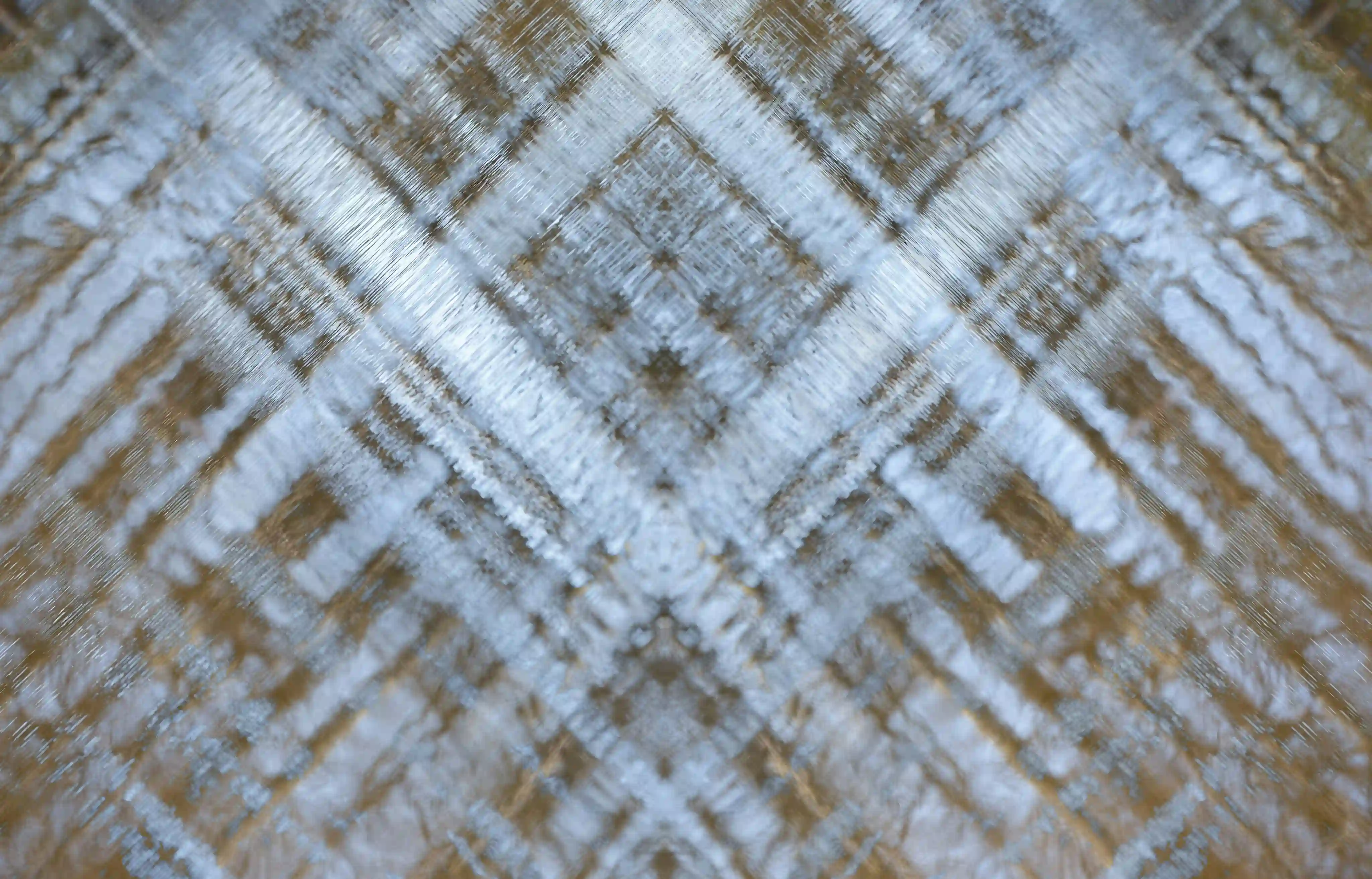 Abstract close-up of a textured surface with crisscrossing light blue and brown patterns.