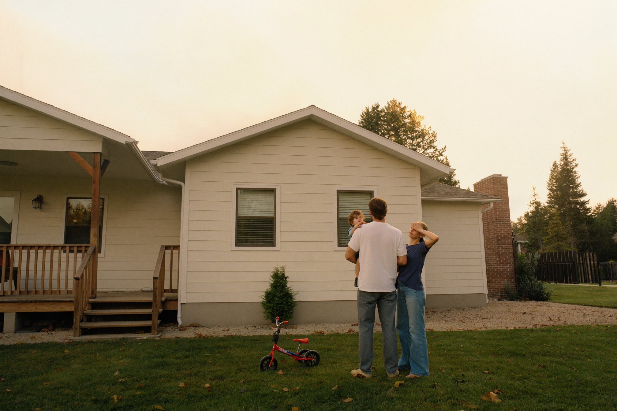 A young family looking up at their Edmonton home in golden evening light