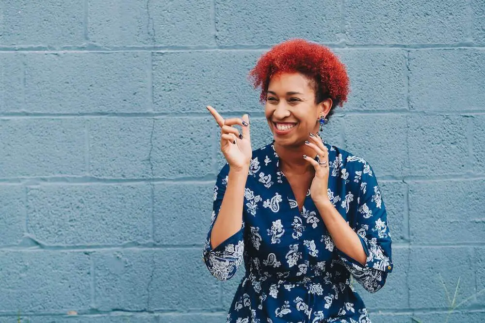 A woman laughing nervously while waving her finger thinking about starting therapy.