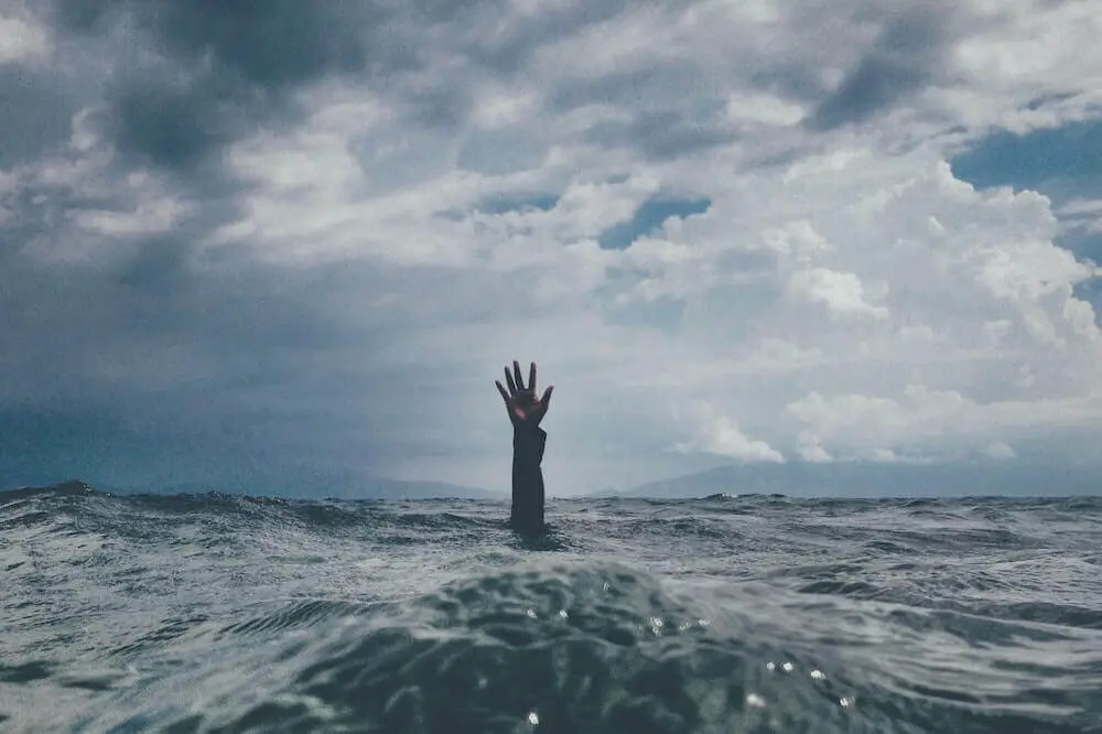 A person reaching out their hand for help while being submerged under water.