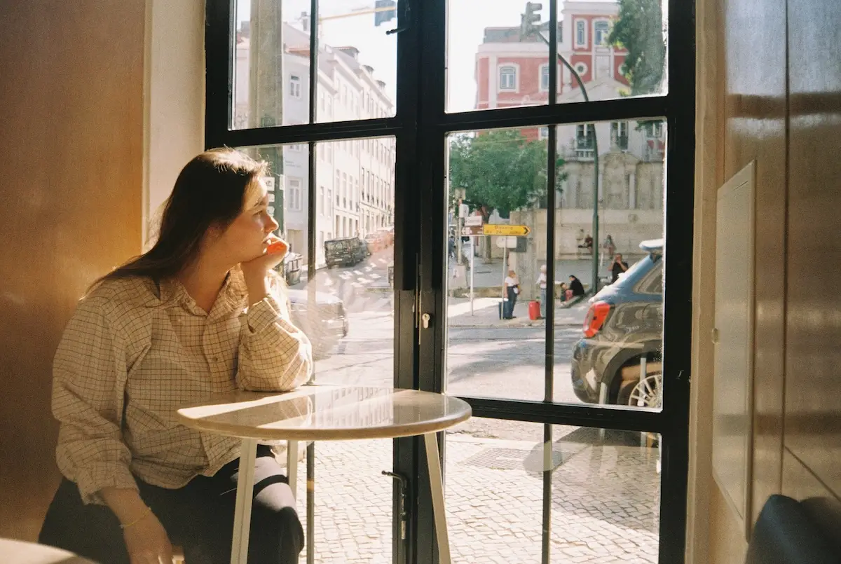 girl pondering looking out the cafe window reflecting therapy 