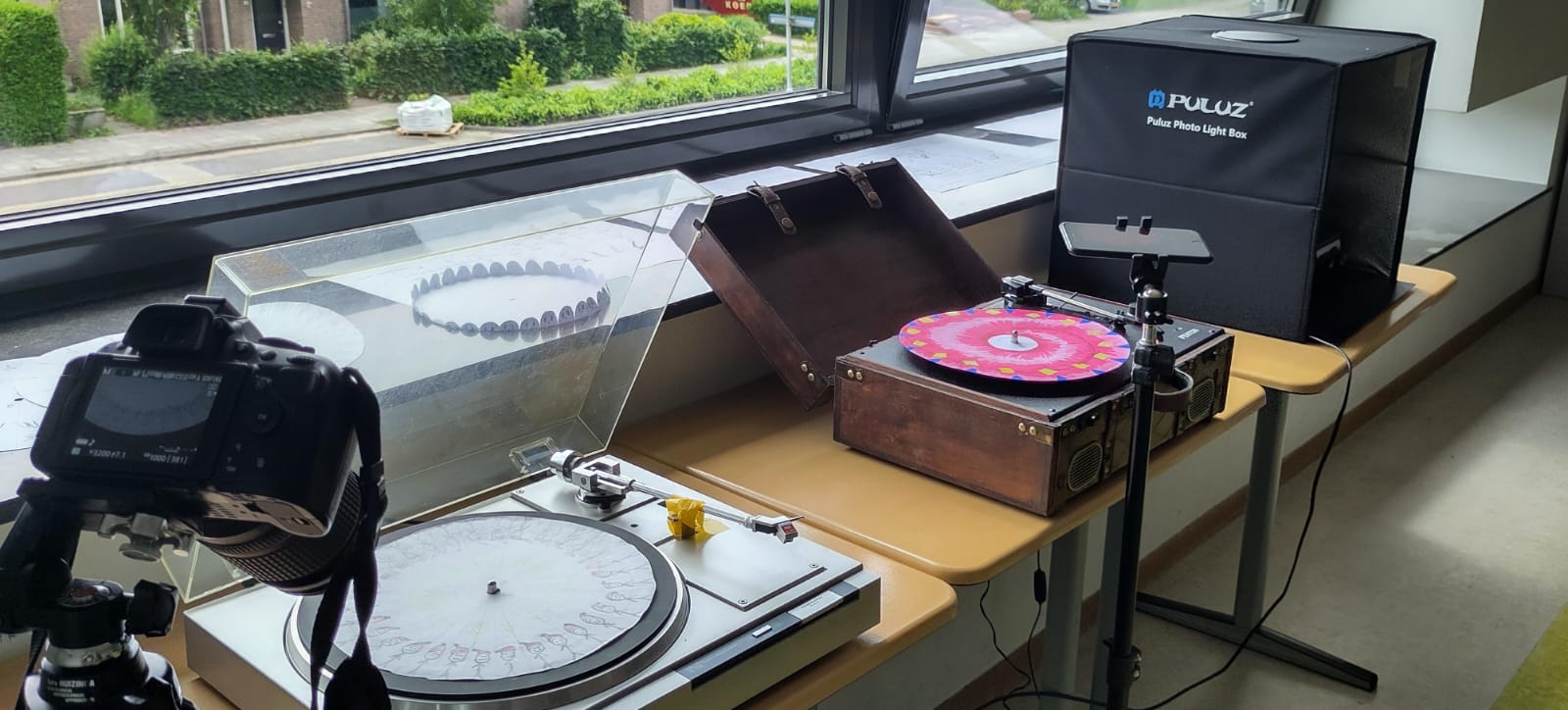 Turntables with phonotrope discs and a camera set up near a window with a Puluz photo light box.