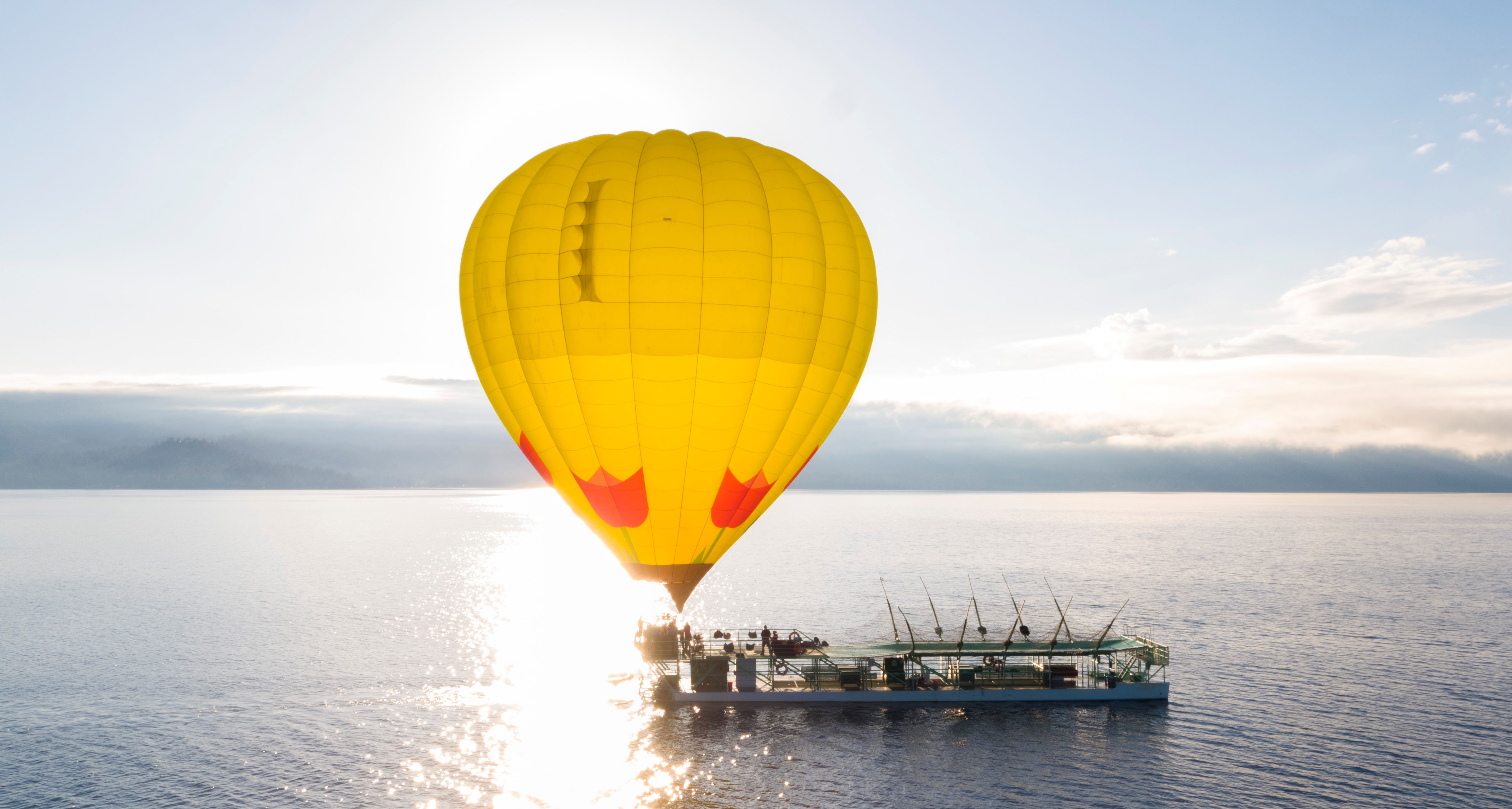 Balloon glowing gold at sunrise beside the launch boat