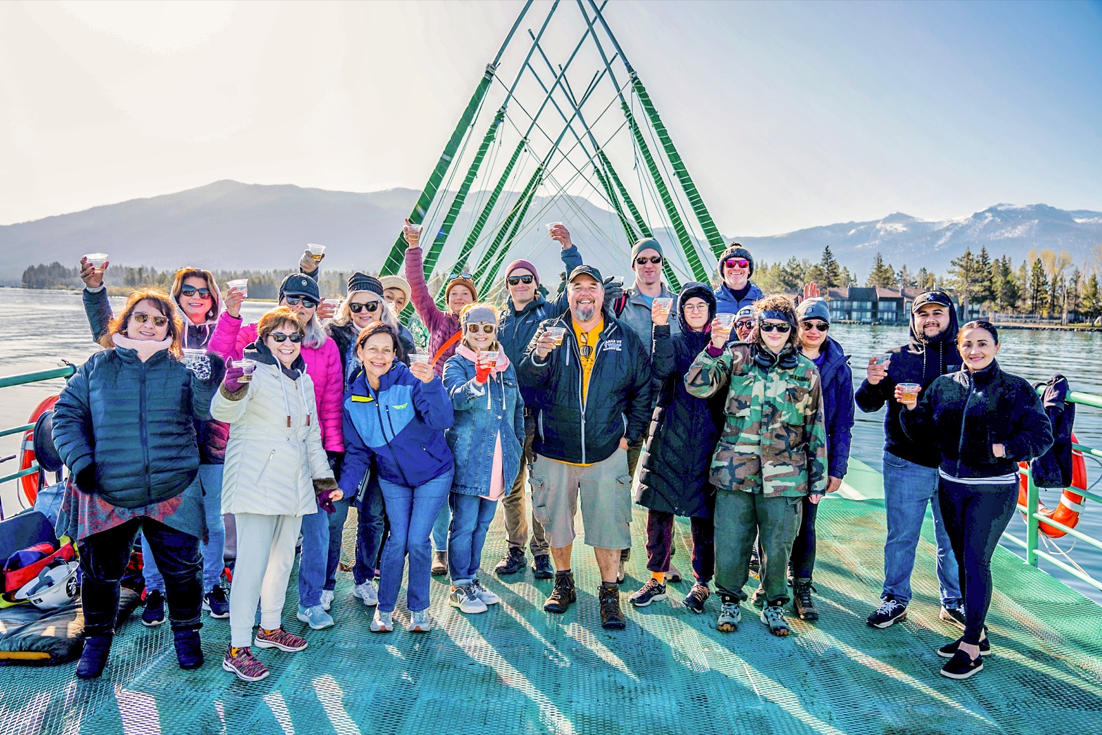 A group raising a toast on the boat deck with the Sierra peaks behind