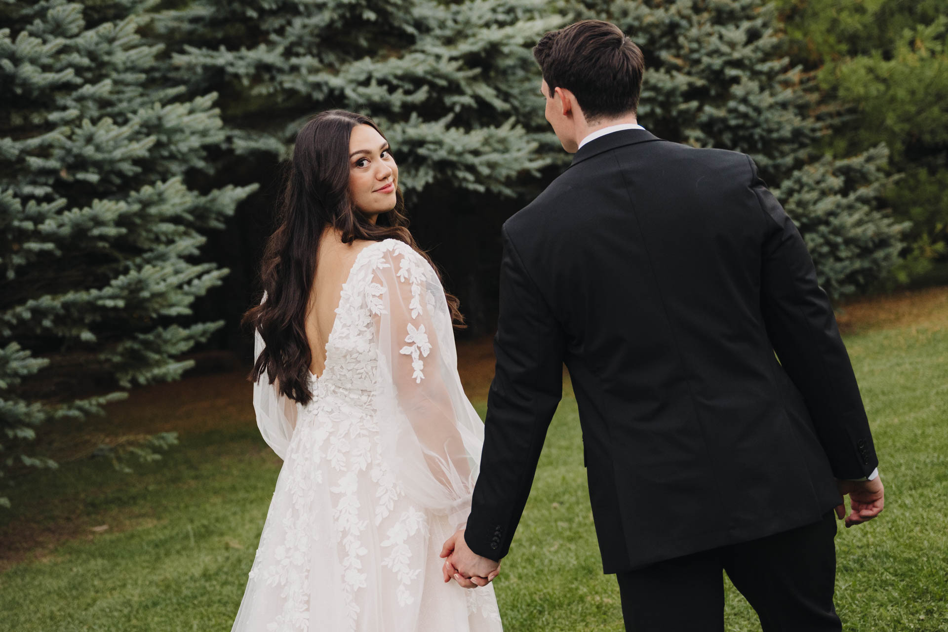 Bride looking over her shoulder while walking with the groom.