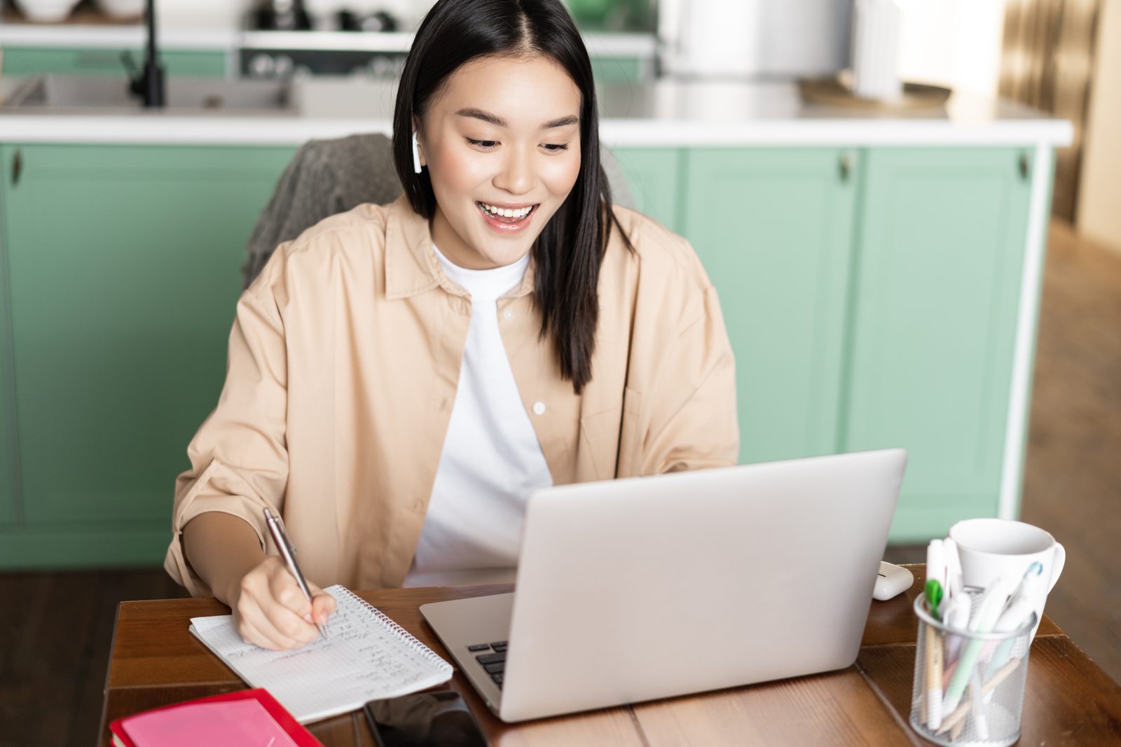 Parent taking notes during a video call at home