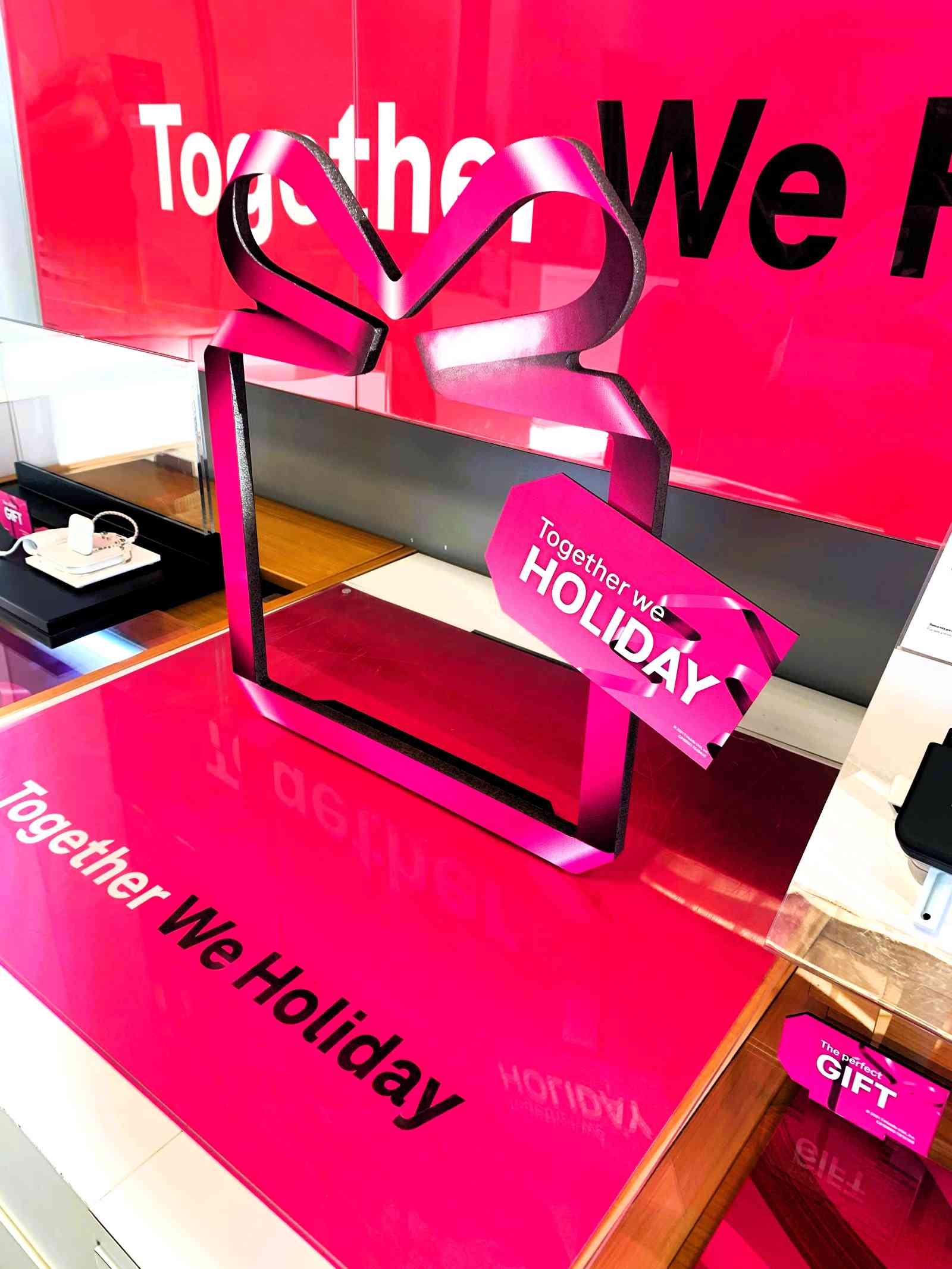 A holiday retail display of a box outline with a ribbon cutout and a gift tag reading "Together we HOLIDAY"_