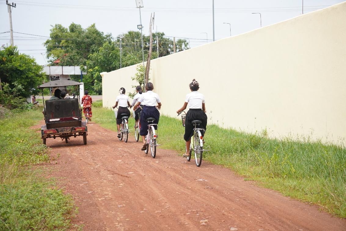 A group of people riding bicycles on a dirt roadAI-generated content may be incorrect.