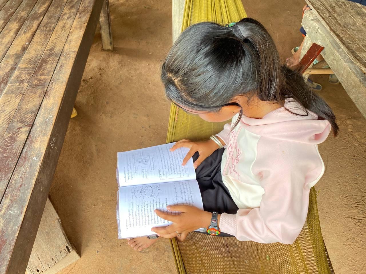 A child sitting on a hammock reading a bookAI-generated content may be incorrect.