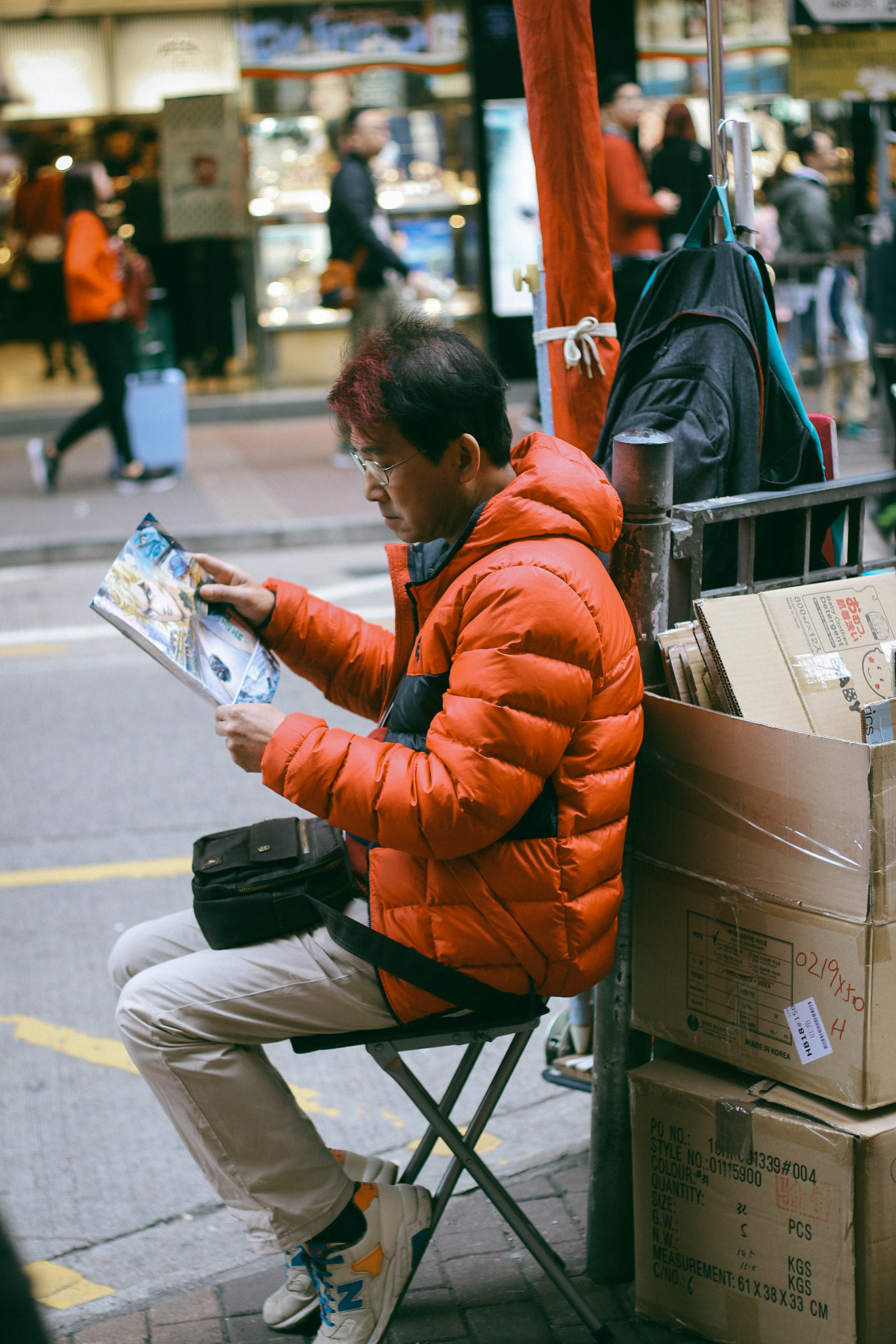 Man sitting on the sidewalk wearing a bright red padded jacket