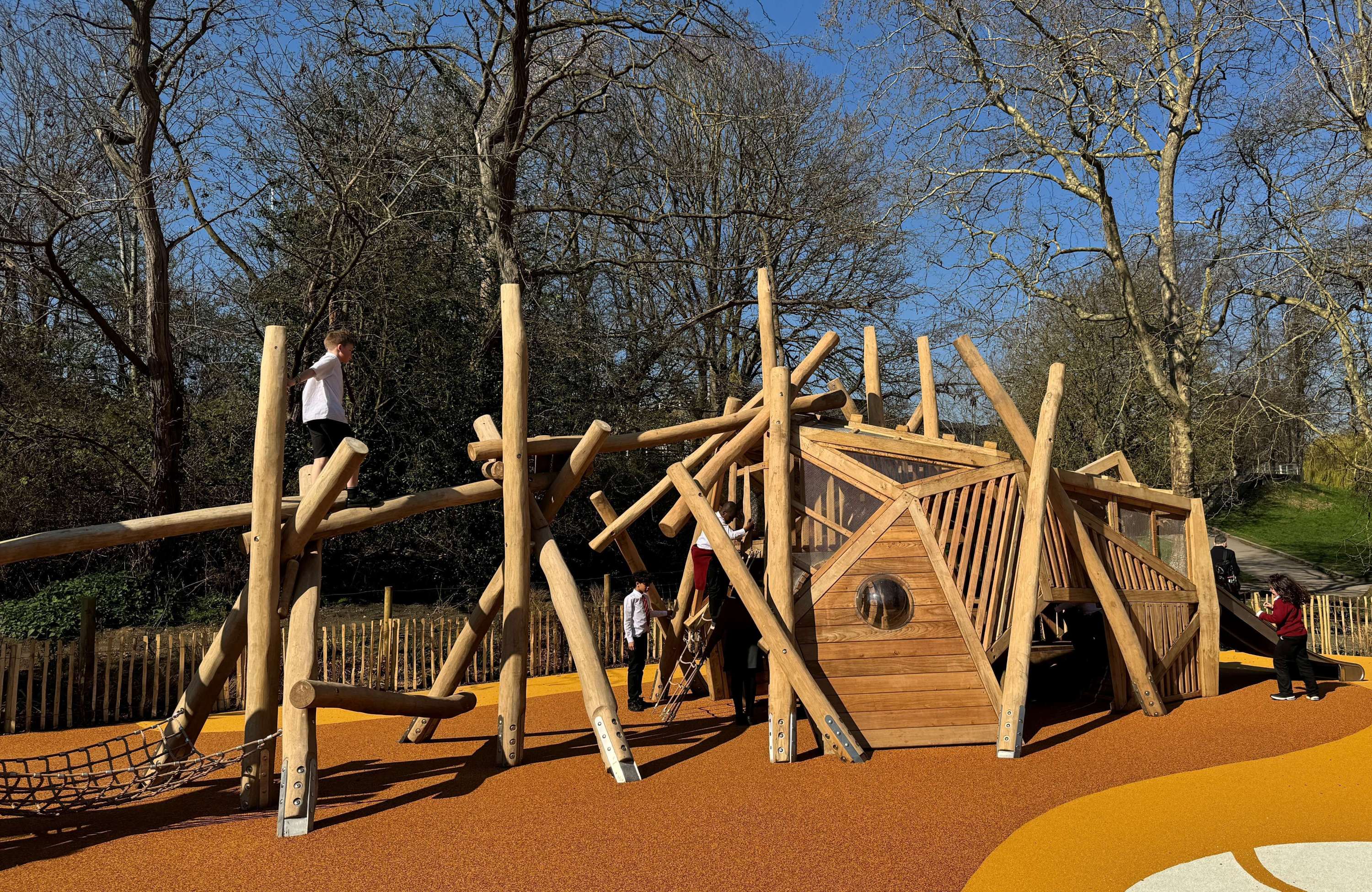 Children playing in the new playground on a sunny day with blue sky.