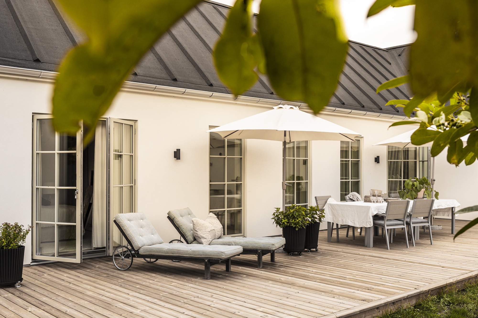 Avkopplande uteplats framför ett klassiskt stenhus från dast med listtäkt papptak och spröjsade fönsterpartier