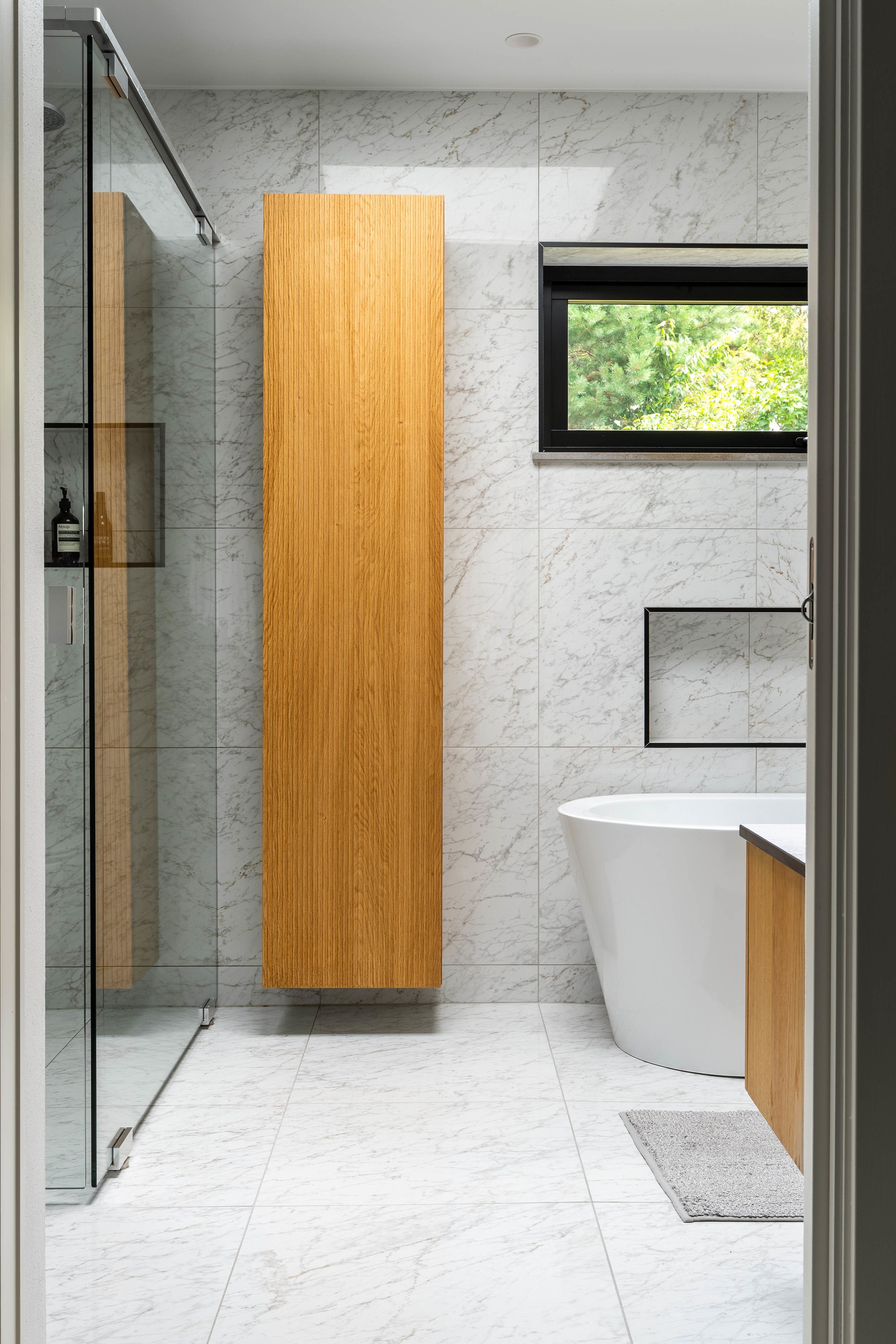 Dast stenhus badrum med inredning och material i sten, glas och trä.